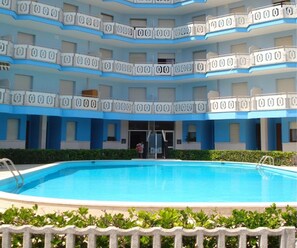Ein mehrgeschossiges Hotel mit einem Schwimmbecken im Vordergrund.