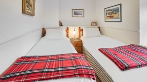Une chambre double avec deux lits, une table de chevet avec une lampe et des tableaux encadrés aux murs.