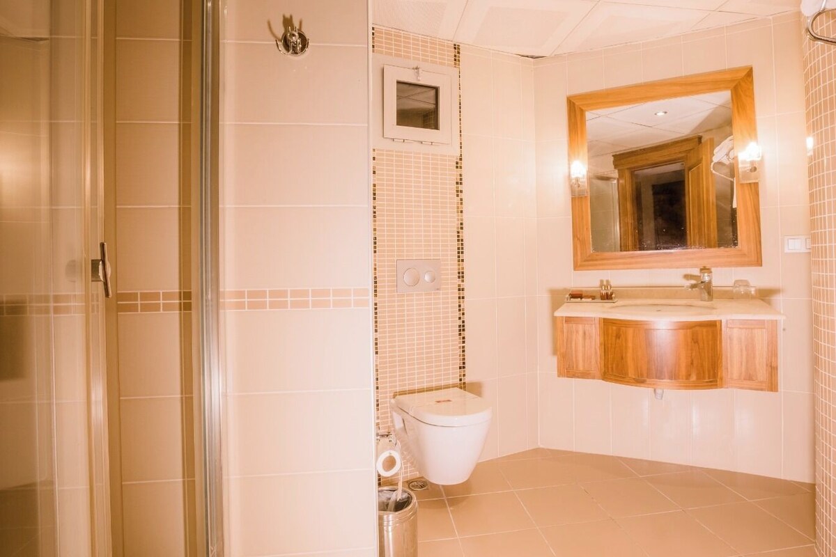 Un baño con ducha, inodoro y tocador con espejo.