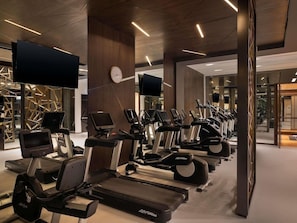A gym with treadmills, stationary bikes, and ellipticals, with a clock on the wall and a TV screen. - Sofitel Riyadh Hotel & Convention Centre (Riyadh)