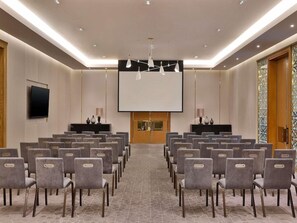 A conference room with rows of chairs, a large screen, and a podium. - Sofitel Riyadh Hotel & Convention Centre (Riyadh)