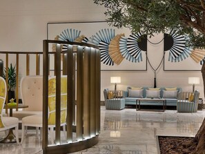 A modern lobby with a seating area, a decorative wall, and a tree.