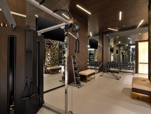 Un gimnasio con equipo de ejercicio, bancos y un espejo grande.