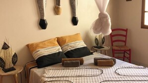 A bedroom with a bed, a bedside table, a chair, and decorative items on the wall. - Villa à la Martinique - Balata district - Near the Balata gardens (Fort-de-France)
