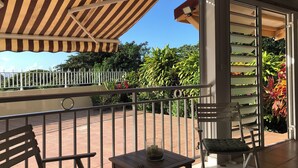 A balcony with a striped awning, a wooden table with a candle, and a chair. - Villa à la Martinique - Balata district - Near the Balata gardens (Fort-de-France)