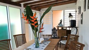 A dining area with a wooden table, chairs, and a vase with flowers. - Villa à la Martinique - Balata district - Near the Balata gardens (Fort-de-France)