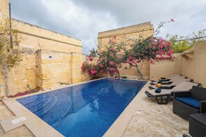 A swimming pool with lounge chairs and a flower bush. - Ellie Boo - Farmhouse w/ Pool, Hot Tub, Games Room (Xewkija)