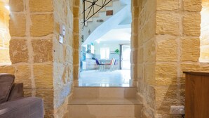 A stone staircase leading to a dining area with a view of the kitchen and living space. - Ellie Boo - Farmhouse w/ Pool, Hot Tub, Games Room (Xewkija)