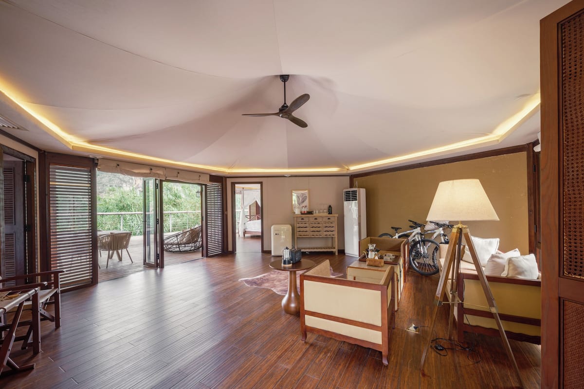 A spacious living area with a ceiling fan, a sofa, a table, and a bicycle.