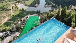 An infinity pool with a view of a river and mountains. - Z-Cliff Hotel (Qianxinan Buyei and Miao)