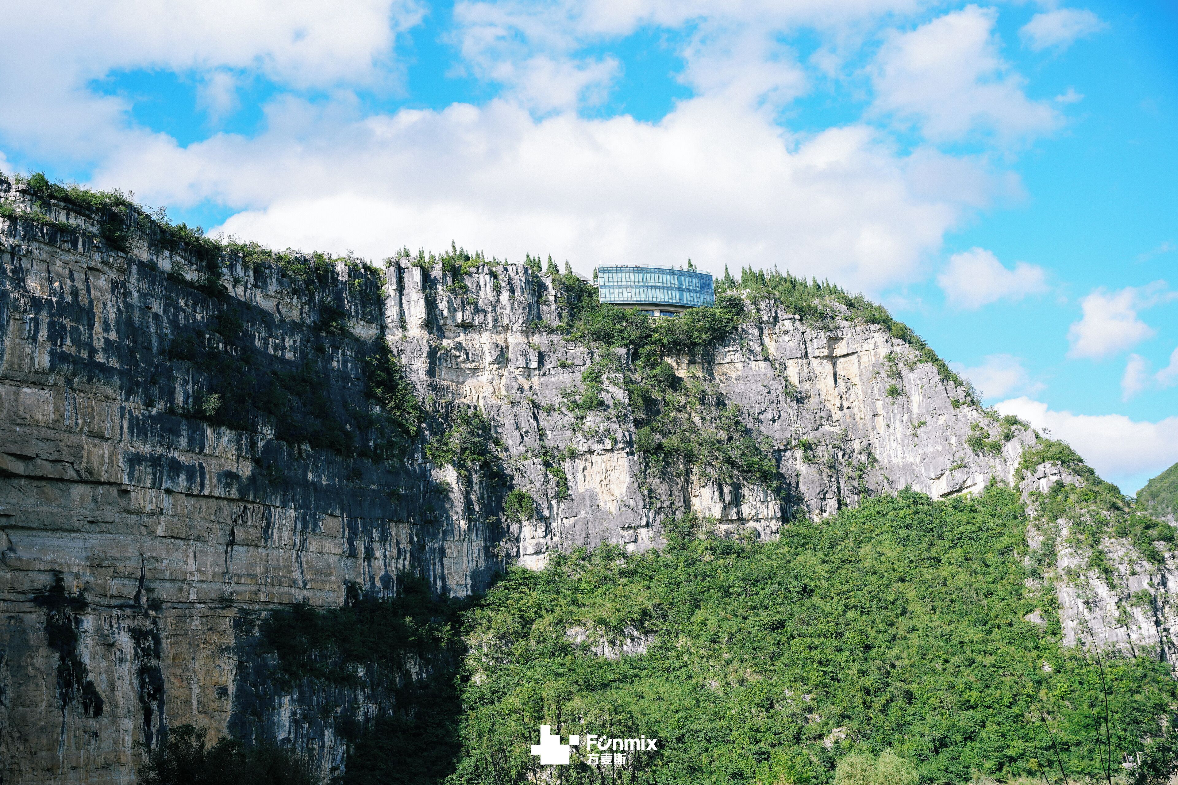 A modern building on a cliff with a view of the surrounding landscape.
