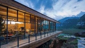 A modern building with large glass windows and a wooden deck overlooking a valley. - Z-Cliff Hotel (Qianxinan Buyei and Miao)