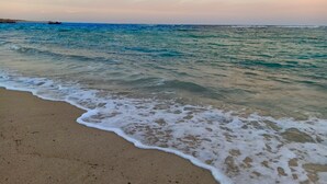 Une plage à l’eau d’un bleu limpide et aux vagues douces.