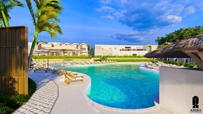 Relax by the resort pool surrounded by palm trees and lounge chairs.