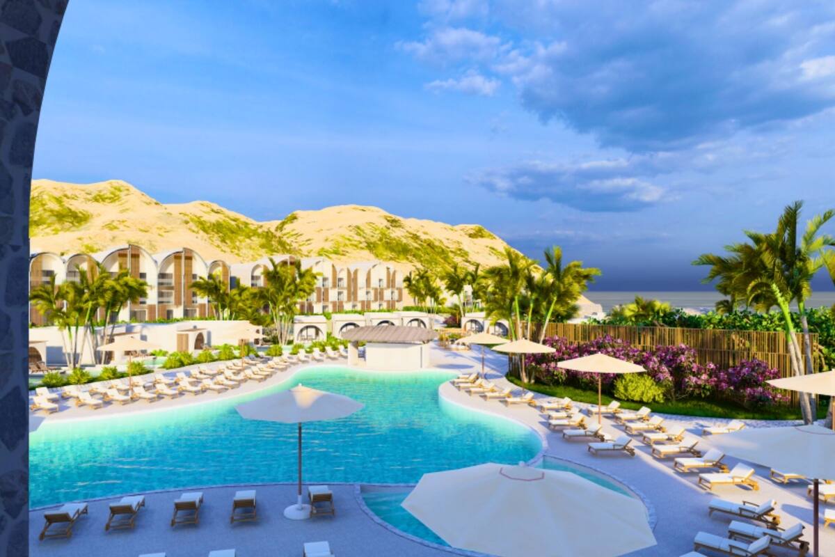 A resort with a large pool, sun loungers, and palm trees.