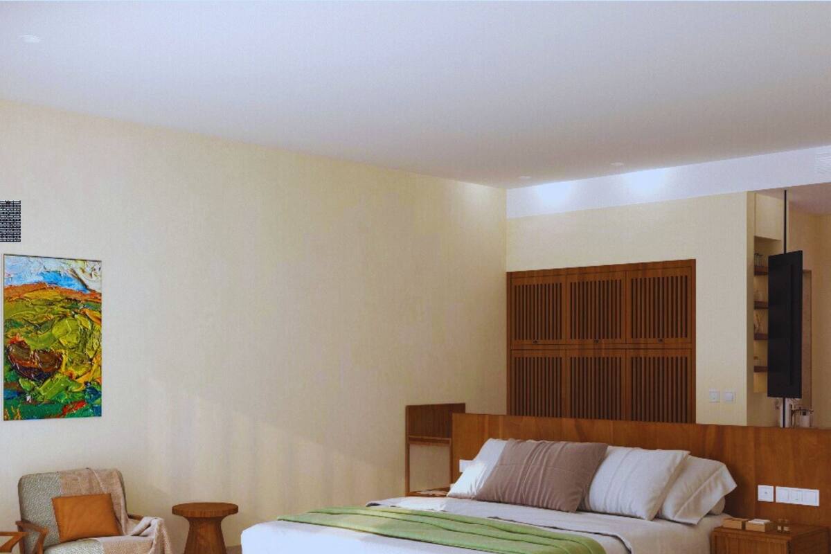 A bedroom with a wooden bed, a chair, a small table, a painting, and a wooden headboard.