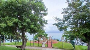 A park with playground equipment, a bench, and a view of the sea.