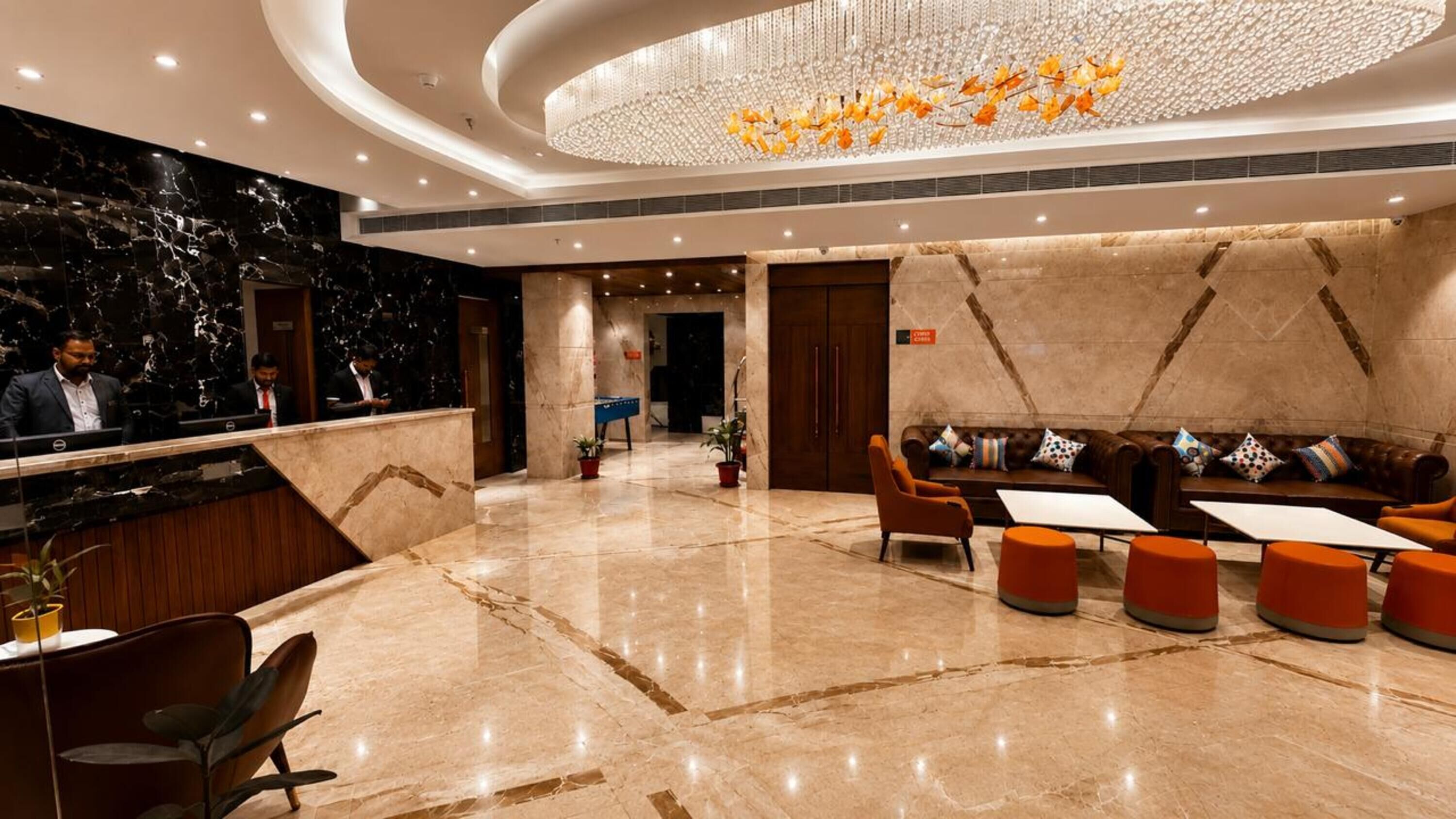 Un vestíbulo de hotel con una recepción, zona de estar y un candelabro.