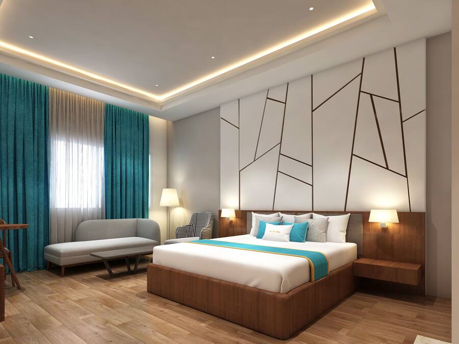 A modern hotel room with a bed, a sofa, a desk, and a chair.