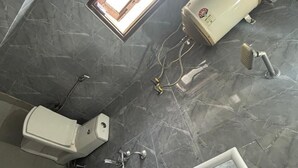 Ein Badezimmer mit Marmorboden, Toilette, Waschbecken, Bidet und einem Fenster.