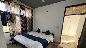 Ein Schlafzimmer mit Bett, Vorhängen, Teppich und einer Tür zu einem anderen Raum.