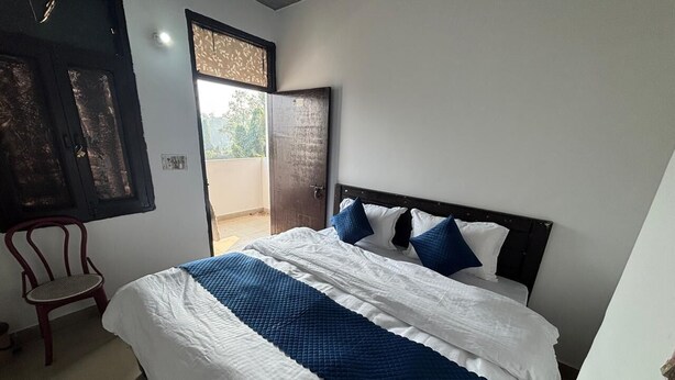 Ein Schlafzimmer mit Bett, Stuhl und einer Tür zu einem Außenbereich.