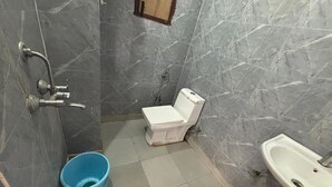 Ein Badezimmer mit Toilette, Waschbecken und einem blauen Eimer.