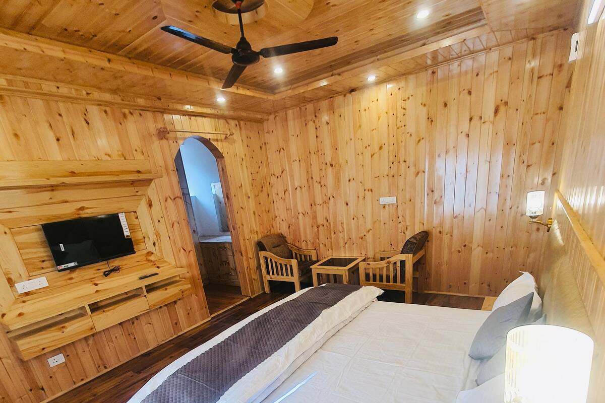 A wooden room with a bed, a TV, and a ceiling fan.