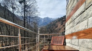 A wooden bench and table on a balcony with a metal railing, overlooking a mountainous landscape. - Ekaant Stays - Manali (Manali)