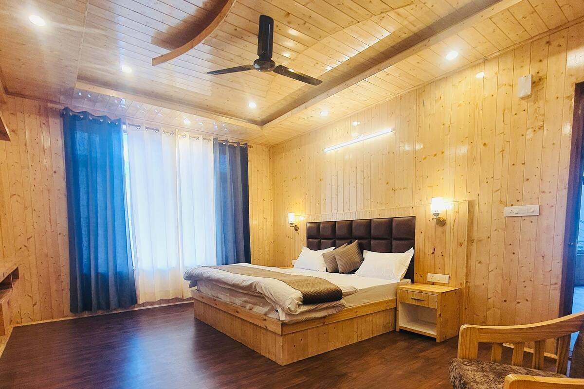 A wooden-paneled room with a bed, a table, and a chair.