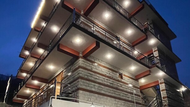 A multi-story building with a modern architectural design, featuring a prominent staircase with illuminated steps and railings. - Ekaant Stays - Manali (Manali)
