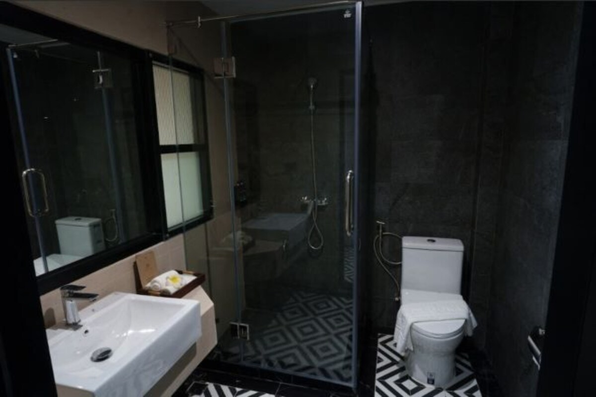 A modern bathroom with a glass-enclosed shower, a white sink, and a toilet.