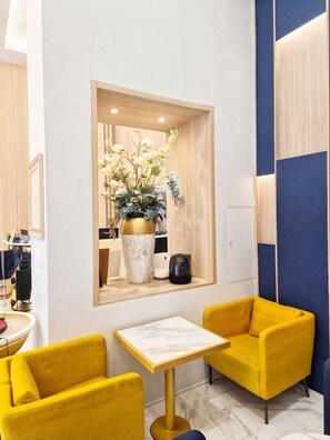 A modern interior with a yellow sofa, a small table, and a decorative plant in a wooden frame. - Khota Hill Hotel (Nakhon Phanom)