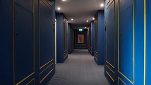 A long, narrow hallway with blue walls and gold trim, leading to a door at the end.