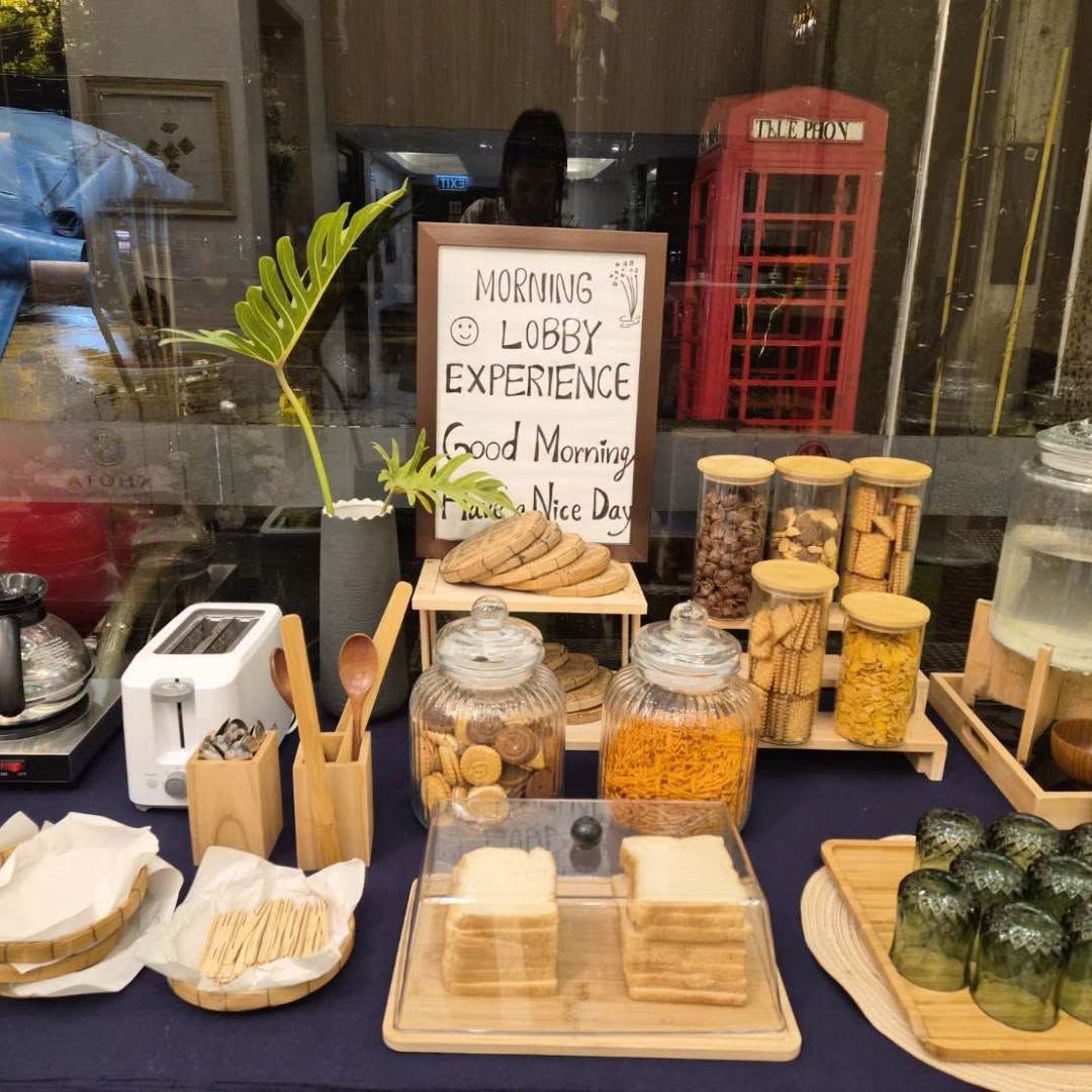A breakfast setup with a sign that reads 'MORNING LOBBY EXPERIENCE' and a red telephone booth in the background.