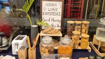 A breakfast setup with a sign that reads 'MORNING LOBBY EXPERIENCE' and a red telephone booth in the background.
