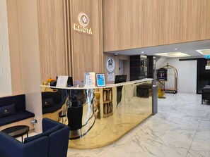 A reception desk with a logo, a computer, and informational brochures. - Khota Hill Hotel (Nakhon Phanom)