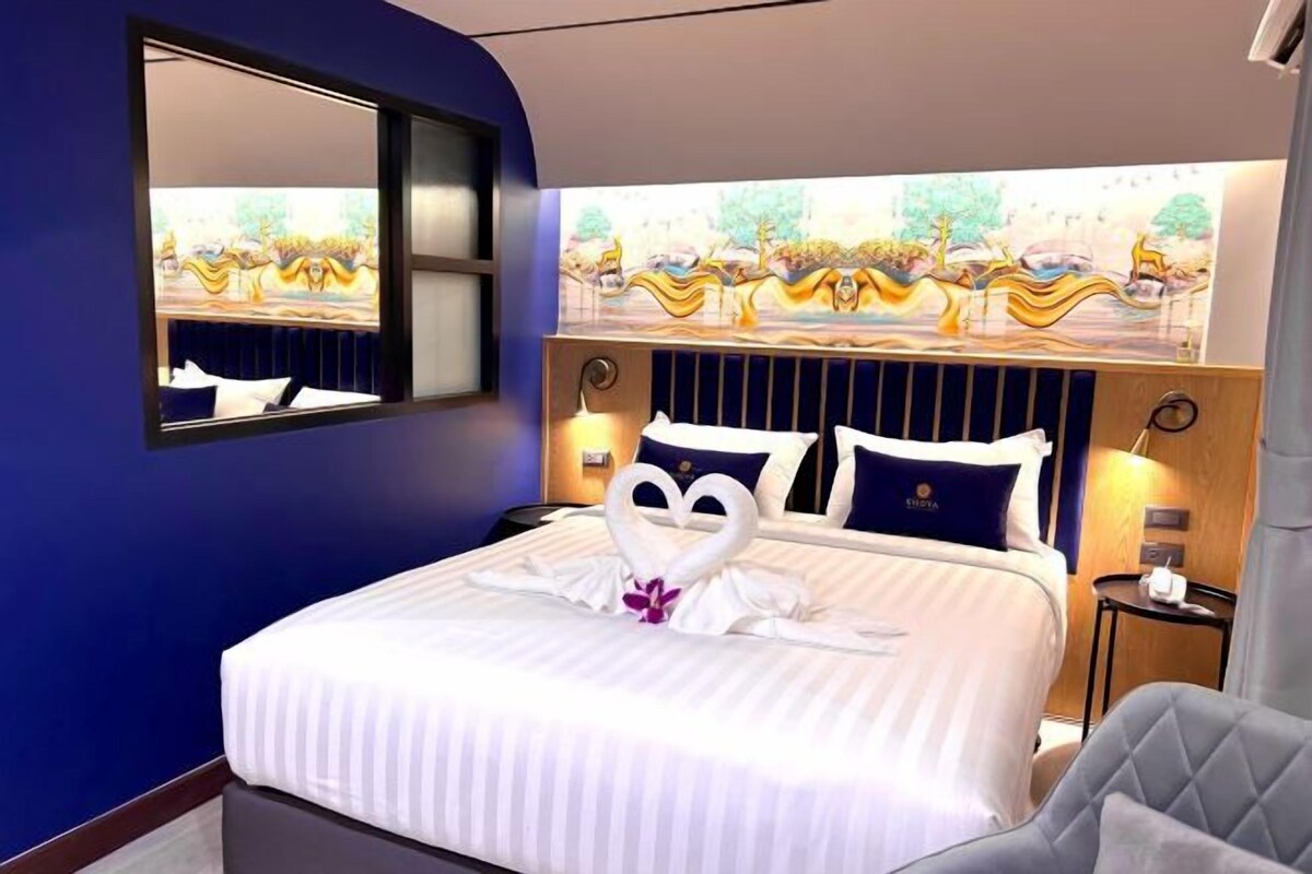Una habitación de hotel con una cama grande, un cabecero con un mural y una mesita de noche con una lámpara.
