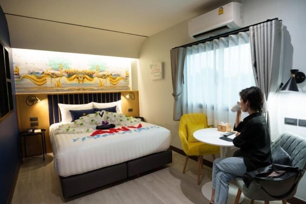 Una habitación de hotel con una cama, una mesita, una silla y una ventana con cortinas.