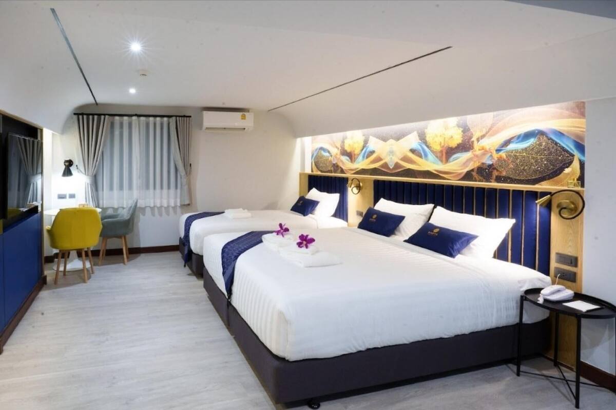 Una camera d'albergo con due letti, una scrivania, una sedia e un grande pannello decorativo.