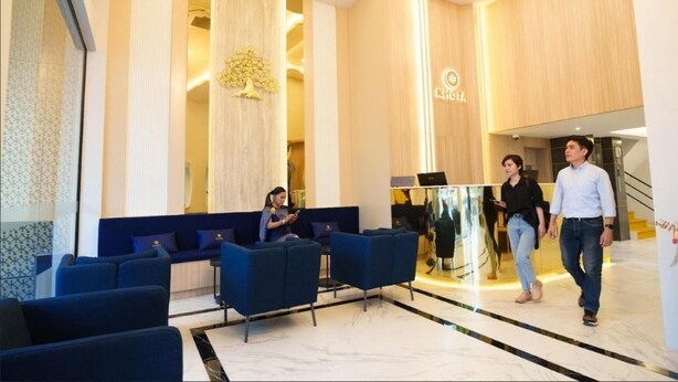 A modern lobby with blue seating, a reception desk, and a logo on the wall.