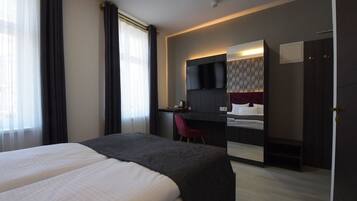 Una habitación de hotel con una cama grande, un escritorio con una silla, un espejo y un armario.