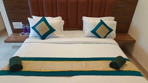 A neatly made bed with white bedding, teal and beige pillows, and a teal and beige bed runner. - Hotel GT Galaxy (Chennai)
