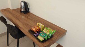 A wooden table with a kettle, snacks, and a chair. - Hotel GT Galaxy (Chennai)