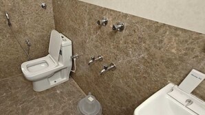 A modern bathroom with a toilet, shower, and sink. - Hotel GT Galaxy (Chennai)
