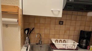 A compact kitchen with a sink, a coffee maker, and a dishwasher.