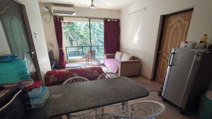 Um espaço de estar compacto com área de jantar, sofá, geladeira e vista para o exterior.