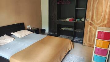 A bedroom with a bed, bedside table, and a wardrobe with shelves.