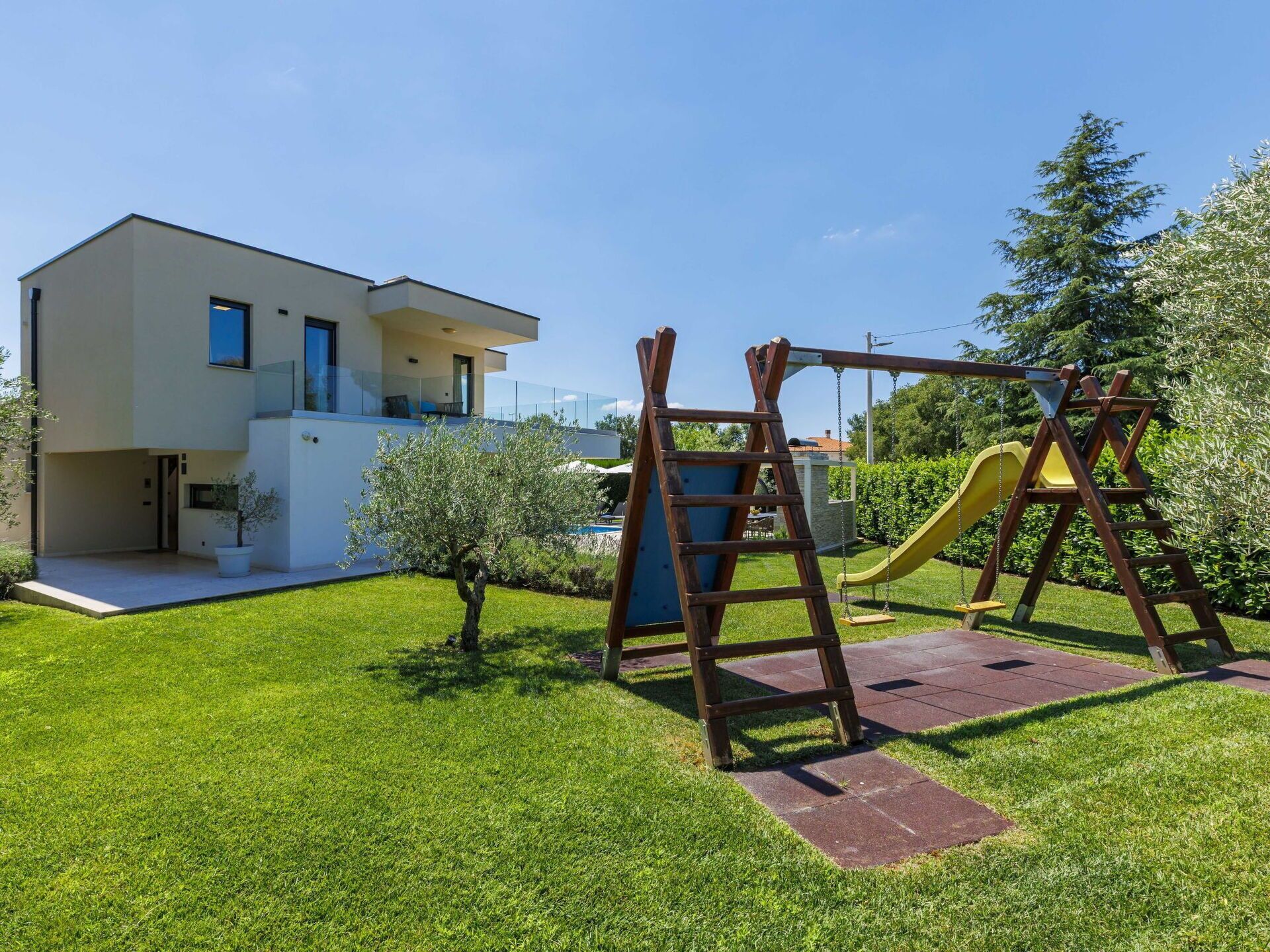 A modern two-story house with a well-maintained lawn and a wooden swing set.