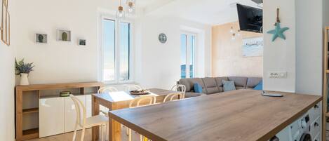 A modern kitchen with a wooden island, white cabinetry, and a built-in washing machine.